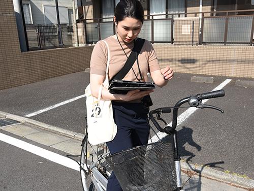 新入社員は顧客の住宅情報が入力されたタブレットを持ち、指定エリアを自転車で回る